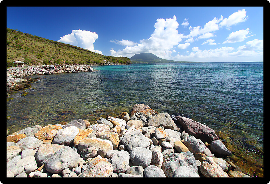 Rocky coastline on the island of Saint Kitts with Nevis in the backdrop.