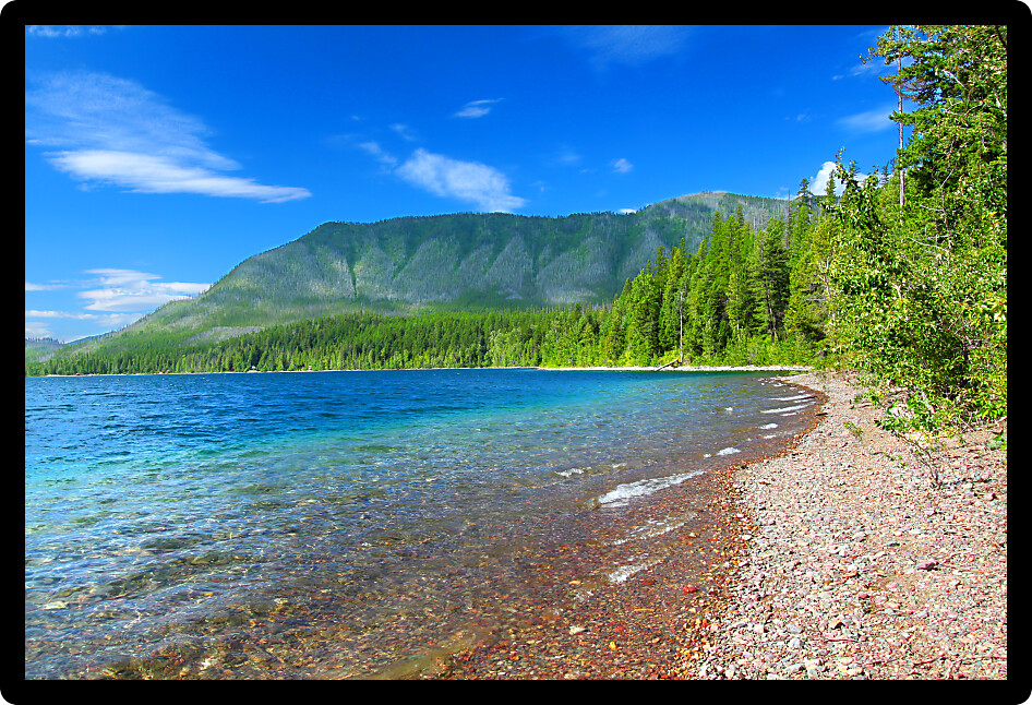 Small waves trickle through bright glacial rocks of Lake McDonald in Glacier National Park.