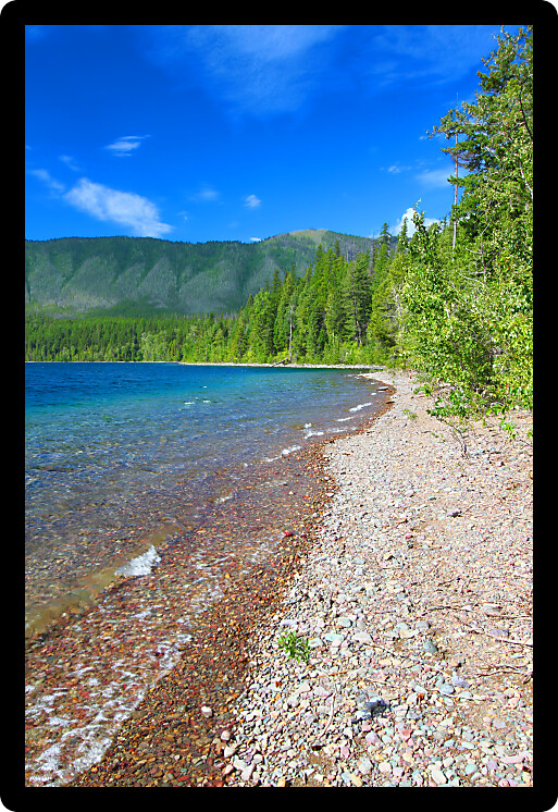 Small waves trickle through bright glacial rocks of Lake McDonald in Glacier National Park.