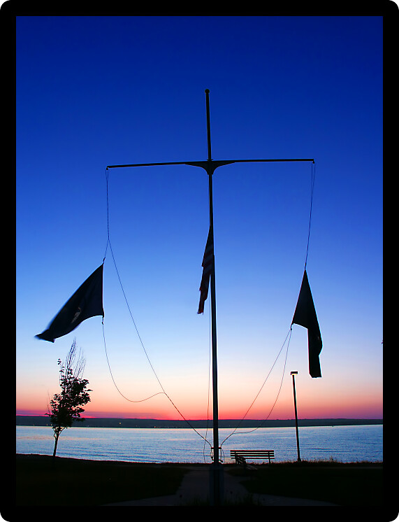 Cross silhouetted against sunset at Lanse Waterfront Park in Michigan.