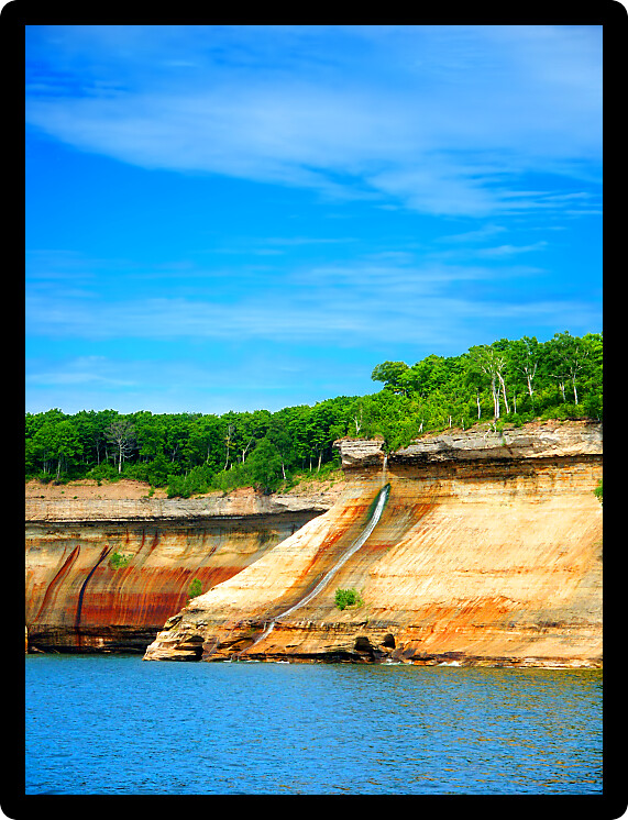 Bridalveil Falls flows down a steep rocky shoreline into Lake Superior at Pictured Rocks National Lakeshore Michigan.