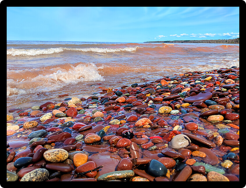 Waves wash up brightly colored rocks along the shoreline of Lake Superior at Porcupine Mountains Wilderness State Park Michigan.