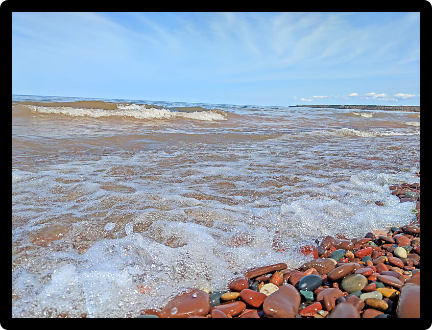 Waves wash up brightly colored rocks along the shoreline of Lake Superior at Porcupine Mountains Wilderness State Park Michigan.