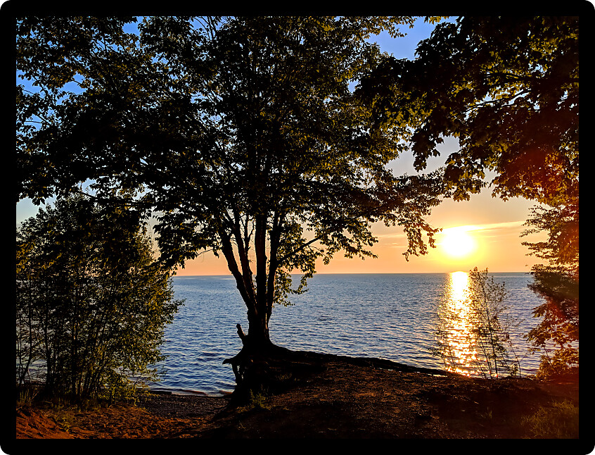 Beautiful Lake Superior sunset framed by dense forest cover of Northwoods Michigan.