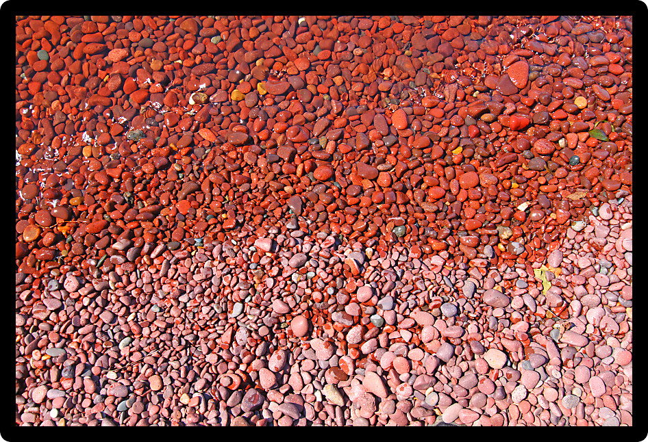Small waves darken the shoreline rocks of Lake Superior in Michigan.