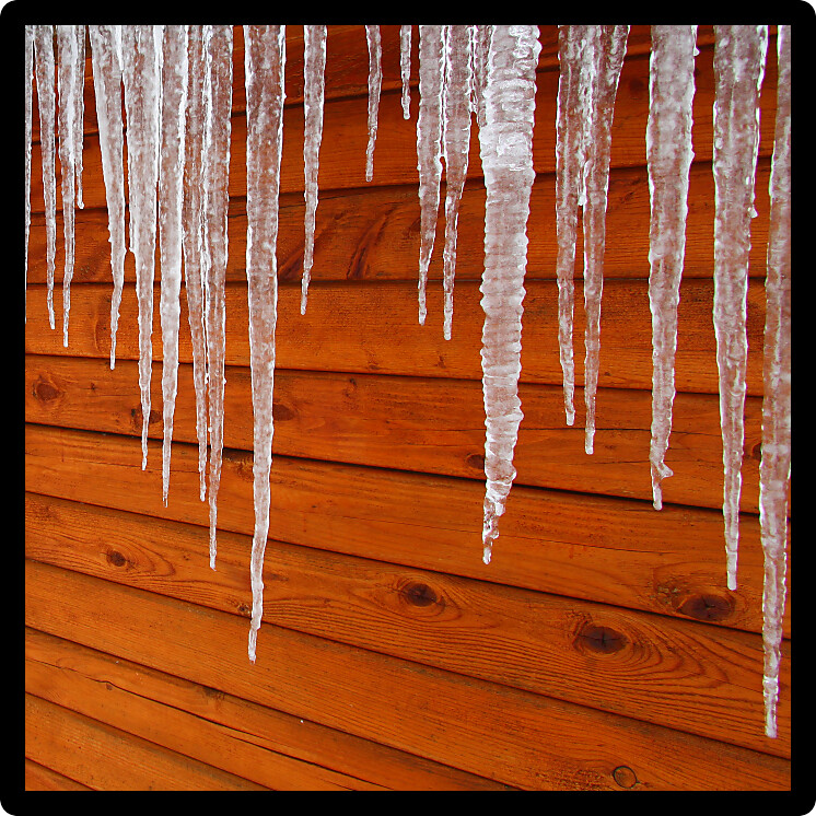Icicles hang from a wood cabin in on a chilly winter day in northern America.
