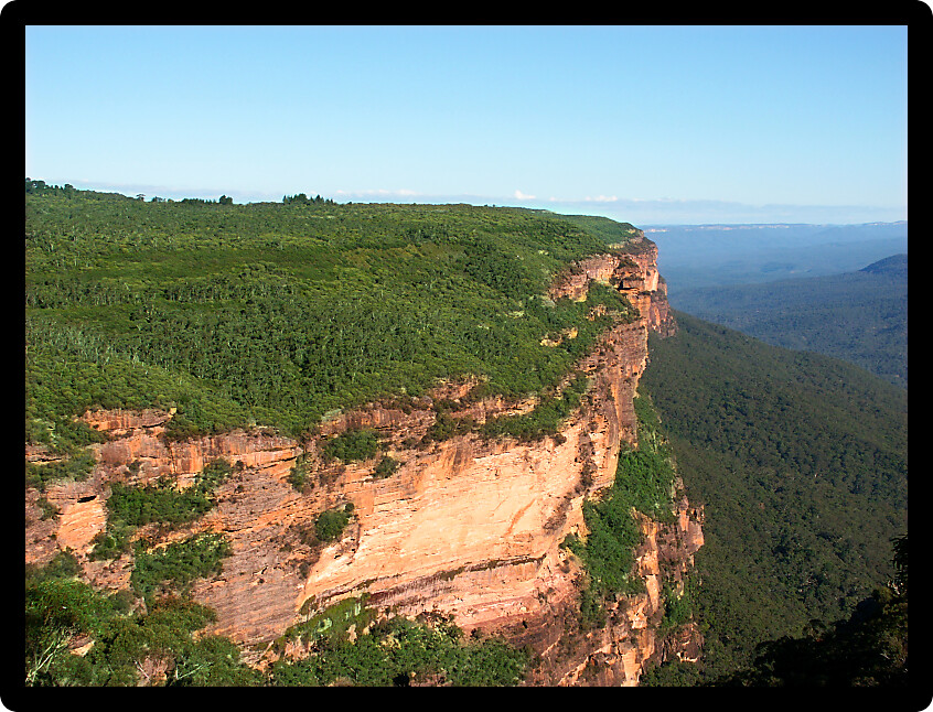 Morning sunlight illuminates a sheer cliff at Blue Mountains National Park of New South Wales Australia.