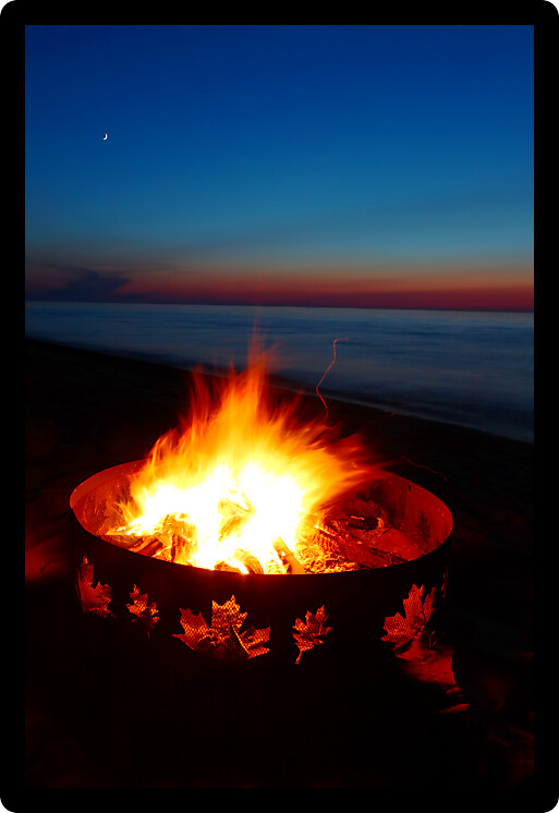 Campfire burns brightly at sunset along the beautiful beach of Lake Superior in northern Michigan.