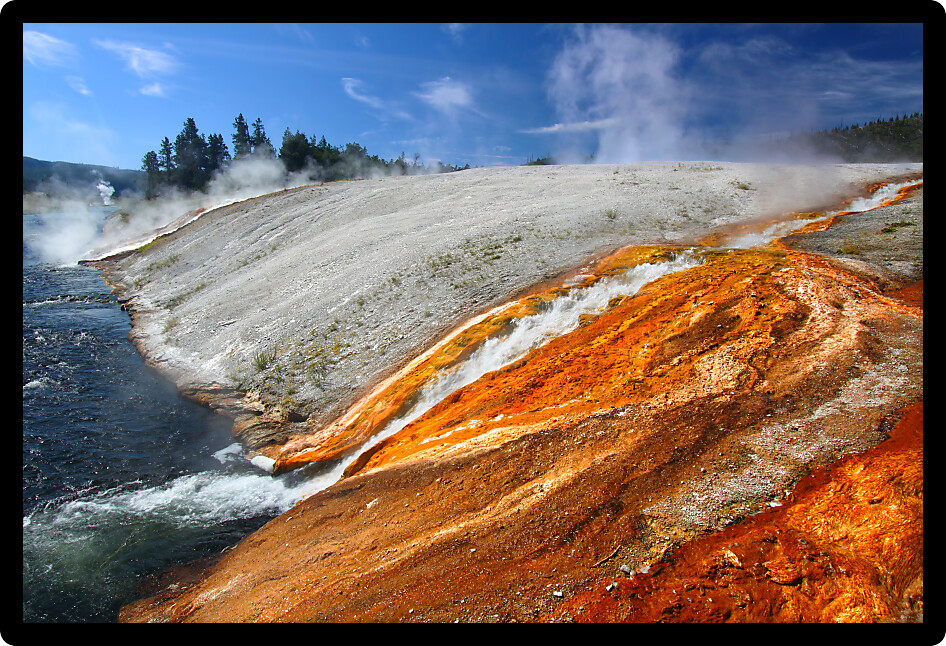 Hot water from the Midway Geyser Basin cascades into the Firehole River in Yellowstone National Park Wyoming.