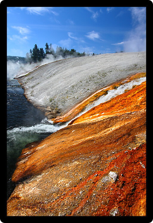 Hot water from the Midway Geyser Basin cascades into the Firehole River in Yellowstone National Park - Wyoming.