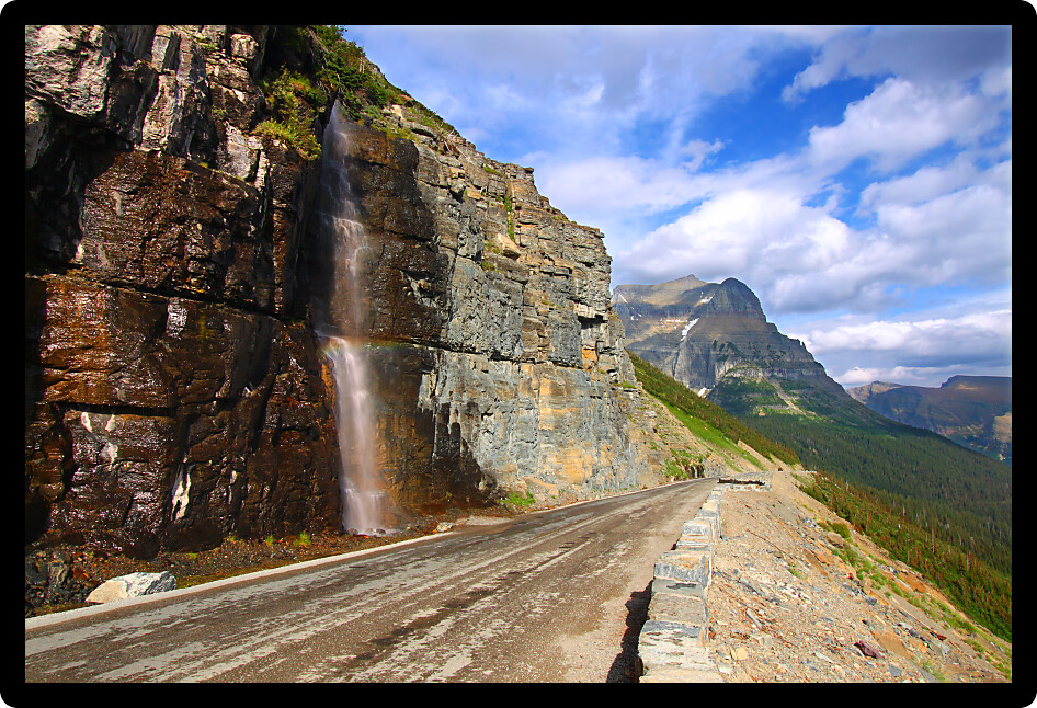 Waterfall flows down from the mountains onto the Going To The Sun Road in Glacier National Park - Montana.