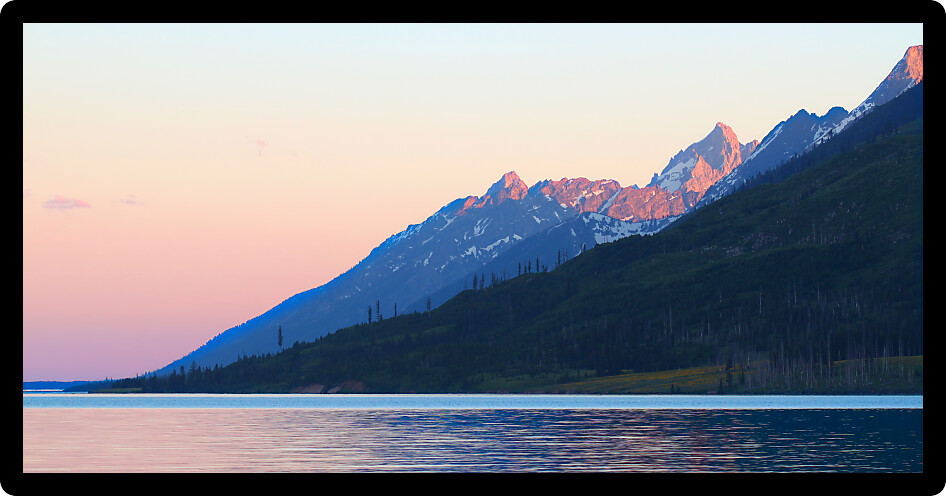 Last rays of sunlight illuminate the peaks of the Grand Teton Mountain Range in Wyoming.