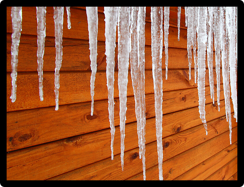 Icicles hang from a wood cabin in on a chilly winter day in northern America.