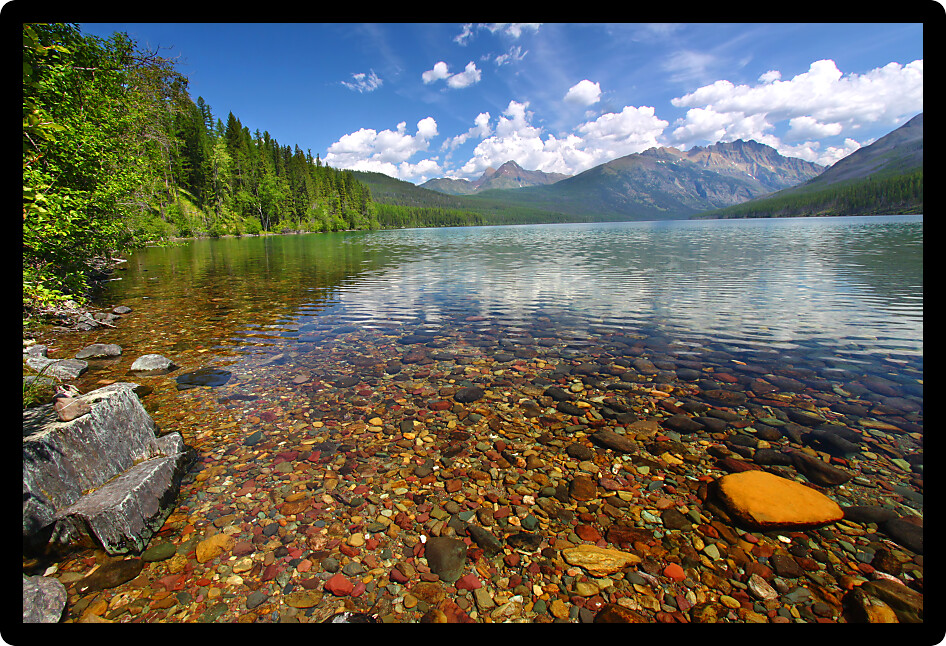 Brightly colored rocks seen through the crystal clear waters of Kintla Lake in Glacier National Park.