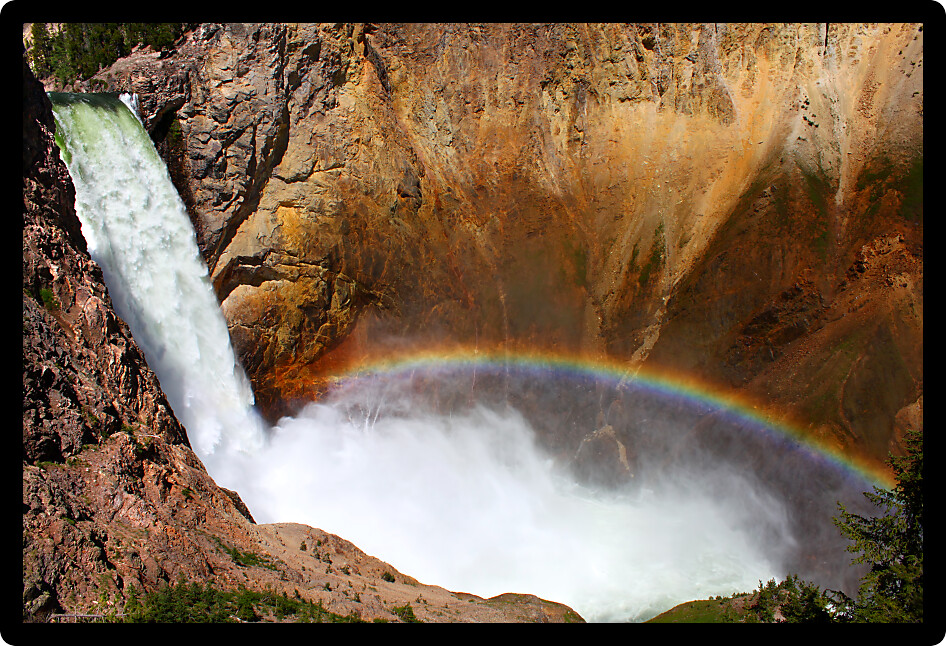 Sunlight creates a rainbow in mists of the Lower Falls of the Yellowstone River in Wyoming.