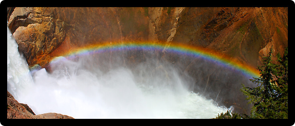 Sunlight creates a rainbow in mists of the Lower Falls of the Yellowstone River in Wyoming.