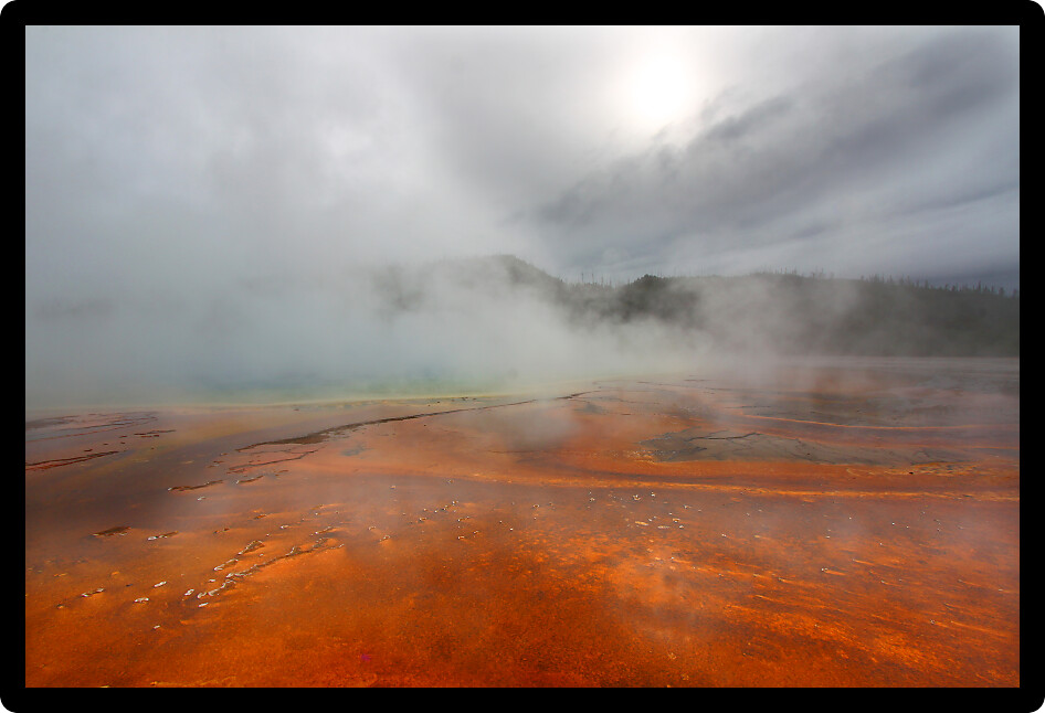 Steam rises from the surface of Grand Prismatic Spring on a cool fall day Yellowstone National Park.