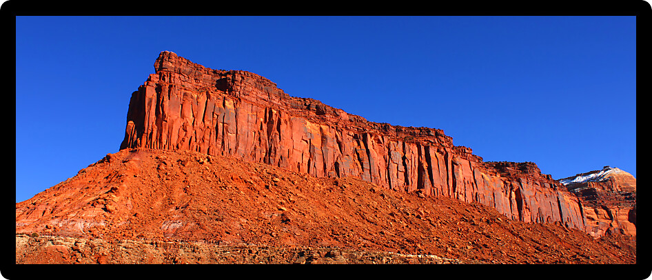 Precipitous rocky cliffs of backcountry Utah against a bright blue sky.