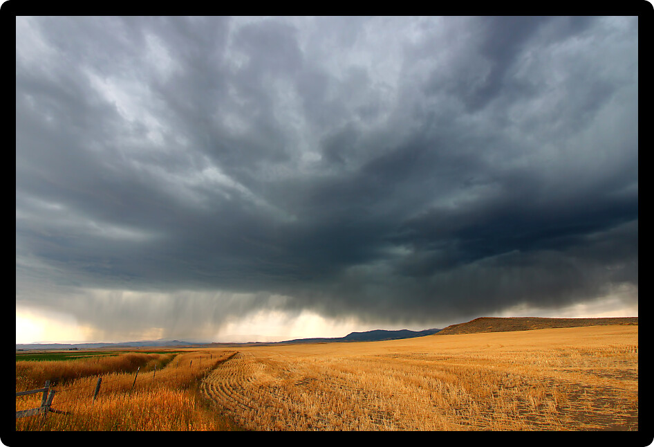 Dark storm clouds thunder across the plains of rural Montana on a fall day.