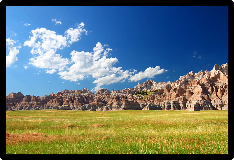 Windswept prairies below jagged mountains in Badlands National Park of South Dakota.