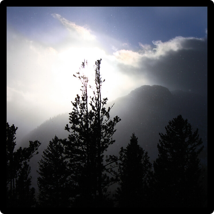 Snowstorm pushes forward against fading sunlight in the Colorado Rockies. 