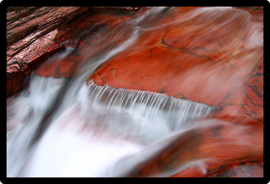 Smooth cascade over red rock in Glacier National Park of Montana.
