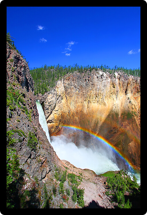 Sunlight creates a rainbow in mists of the Lower Falls of the Yellowstone River in Wyoming.