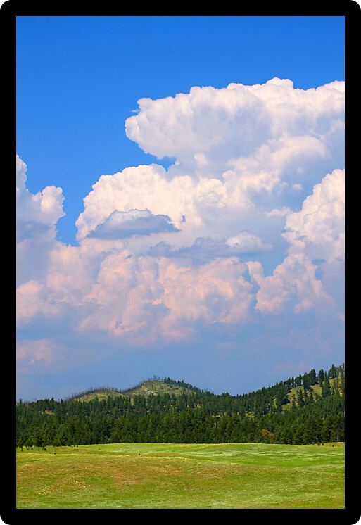 Giant cumulonimbus storm clouds erupt over the landscape of western South Dakota.